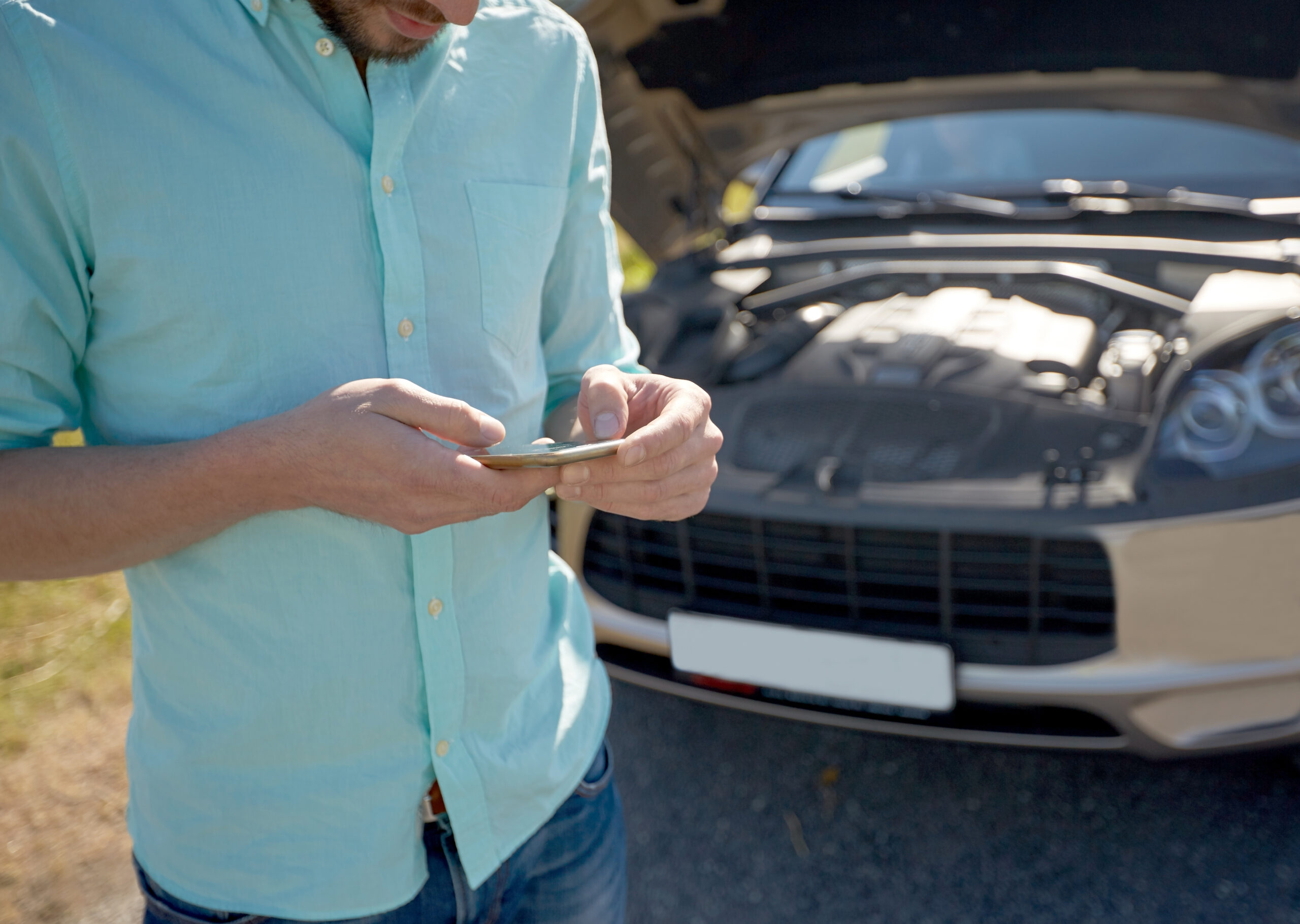 close up of man with smartphone and broken car